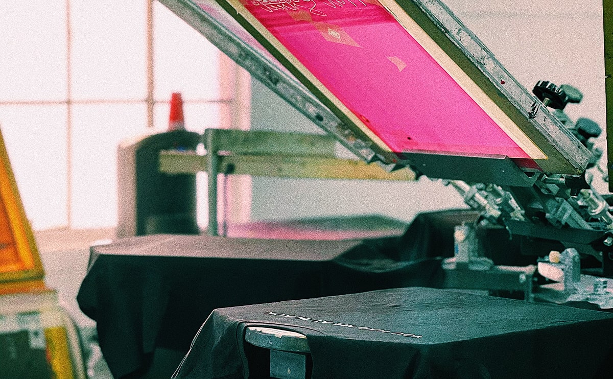 black crewneck t-shirt front view flat lay with magenta screen printing frame aligned over center chest print area
